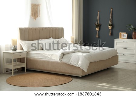 Comfortable bed with soft blanket in stylish room interior