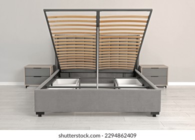 Comfortable bed with storage space for bedding under lifted slatted base in room