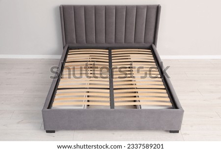 Comfortable bed with storage space for bedding under slatted base in room, above view