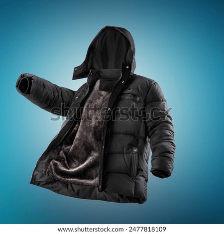 Comfortable black puffer jacket with warm fur lining and snug hood, decorated with stainless steel rivets, levitating with unzipped zipper against blue gradient backdrop. Stylish mens winter clothing 