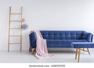 Comfortable Blue Sofa With Blanket In Simple White Room