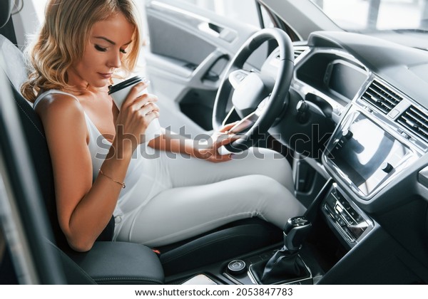 Comfortable car. Woman in formal clothes is\
indoors in the\
autosalon.