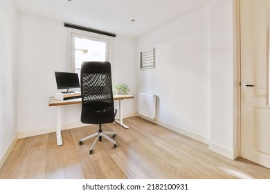 Comfortable Chair Placed Near Table With Computer Monitors Against Blank Whiteboard And Mirror In Light Home Office In Contemporary Flat