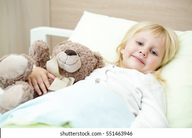 Comfortable and cozy. Adorable little girl resting in a hospital bed with her teddy bear smiling to the camera ambulance hospitalization surgery virus healthcare medicine clinic patient child concept
