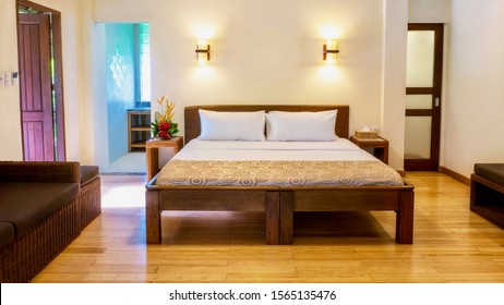 A Comfortable Deluxe Room In An Upscale Boutique Hotel, With A Queen Size Bed, Rattan Furnishings, Wooden Floors, And Natural Light. In The Philippines.