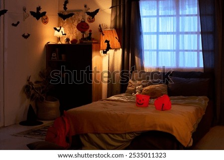 Comfortable double bed with two orange pumpkin shaped buckets for Halloween treats, several cushions and teddybear