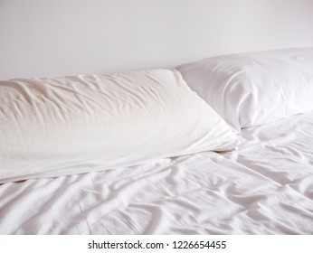 Comfortable empty bed with white clean blankets and comfy pillows. Sleep dream paradise.