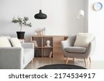 Comfortable grey furniture with wooden shelving unit and black lamp in light living room