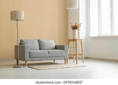 Comfortable grey sofa with lamp and pampas grass in living room