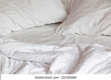 Comfortable, messy bed with pillows and duvet 