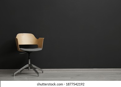 Comfortable Office Chair Near Black Wall Indoors. Space For Text