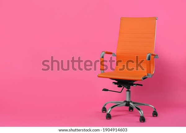 Comfortable office chair on pink background, space\
for text