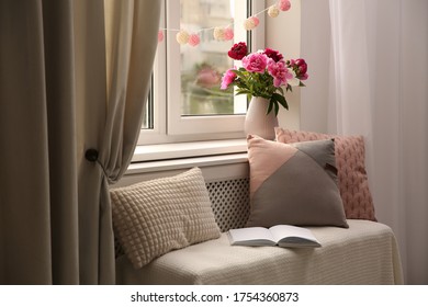 Comfortable place for rest with cushions and peony flowers near window indoors - Powered by Shutterstock