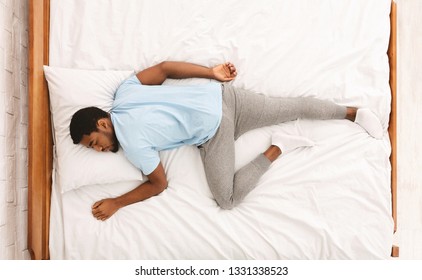 Comfortable Pose For Sleep. Black Millennial Guy Sleeping, Lying On Stomach In Bed, Top View