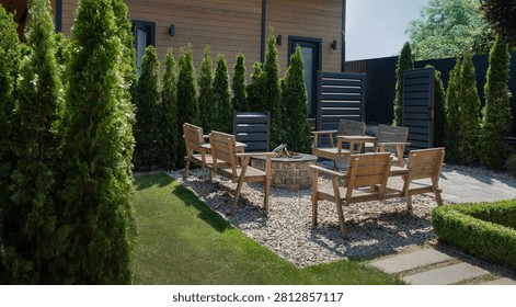 A comfortable seating area, featuring a stone fire pit, wooden benches, and armchairs, serves as a cozy spot for evening gatherings.