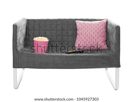Comfortable sofa with popcorn and TV remote control on white background. Home cinema