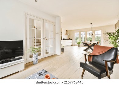 Comfortable sofa with soft cushions located under stylish chandelier in spacious light living room with arch