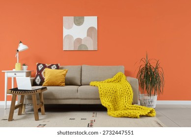 Comfortable sofa, table and laptop in interior of living room