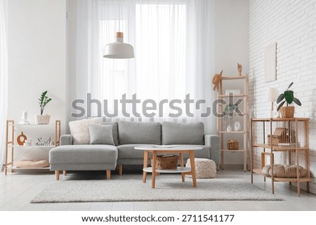 Comfortable sofa and table near window with white curtains in interior of living room