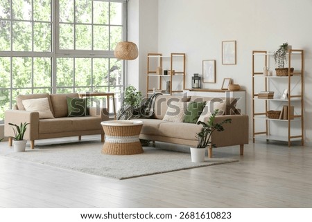 Comfortable sofas, wicker table and houseplants near window in interior of living room