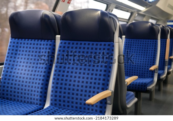 comfortable soft blue seats with headrests in\
half-empty train car in Germany, concept of long-distance travel,\
ticket for stowaways, transporting second-class passengers, being\
late for your train