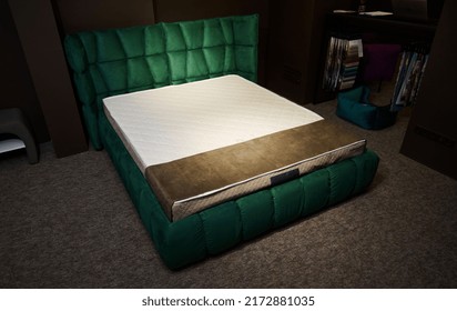 Comfortable Stylish Green Soft Bed With Orthopedic Mattress, Displayed For Sale In A Furniture Design Showroom Against A Stand With Upholstery Fabric Swatches. Bedroom And Home Interior Design