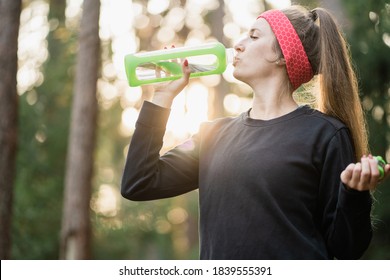 comfortable stylish suit for sports. confident young woman of European appearance brown-haired with a bandage on her head from sweat, after training, resting and drinking clean water from a new bottle - Shutterstock ID 1839555391