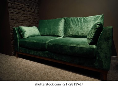 Comfortable upholstered velour green settee displayed for sale in the furniture store showroom. Exhibition of upholstered furniture.