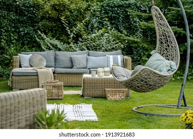 Comfortable wicker garden furniture with grey pillows in beautiful backyard - Shutterstock ID 1913921683