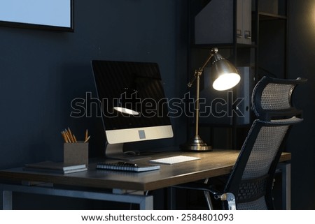 Comfortable workplace with computer and lamp on wooden desk at home office in evening