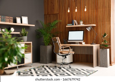 Comfortable workplace with computer near wooden wall in stylish room interior. Home office design - Powered by Shutterstock