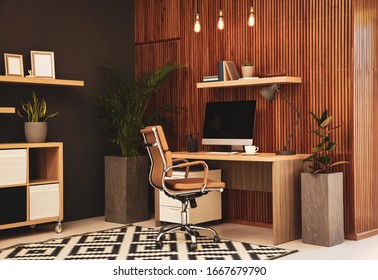 Comfortable Workplace With Computer Near Wooden Wall In Stylish Room Interior. Home Office Design