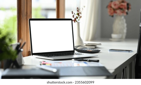 Comfortable workplace, laptop with empty display, documents and calculator on white table