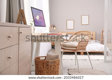 Comfortable workplace with modern computer near window in bedroom. Interior design