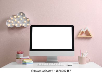 Comfortable workplace with modern computer on table near pink wall. Space for design
