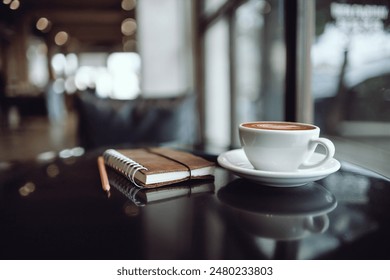 Comfortable workplace on table by the window in modern cafe with coffee drink and  note book, vintage tone