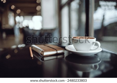 Comfortable workplace on table by the window in modern cafe with coffee drink and  note book, vintage tone