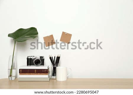 Comfortable workplace with wooden desk near white wall. Space for text