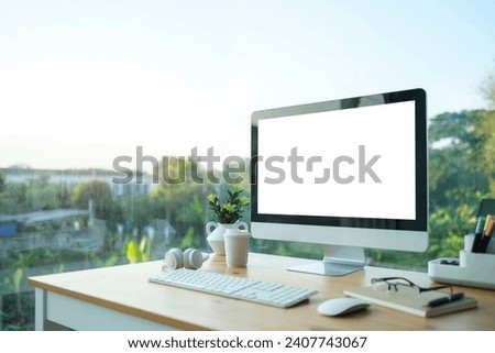 Comfortable workspace with blank screen comput and office supplies on wooden desk.