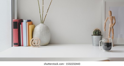 Bequeme Arbeitsfläche mit Büchern, Bürobedarf und Kopienraum auf weißem Holztisch 
