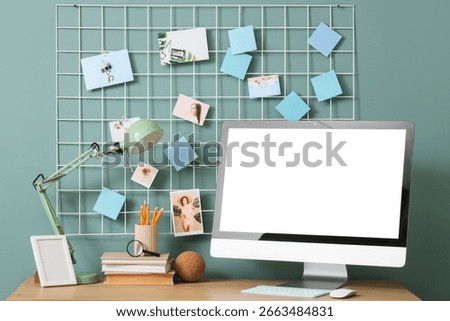 Comfortable workspace with modern computer, desk lamp and mood board near blue wall, closeup