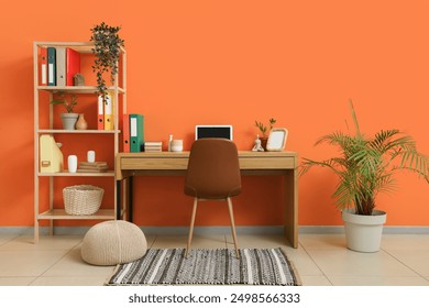 Comfortable workspace with modern laptop near orange wall - Powered by Shutterstock