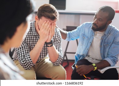 Comforting. Reliable Kind Black Man Putting His Hand On The Shoulder Of A Crying Person While Talking To Him