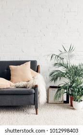comfy couch with flowerpots in white living room interior with brick wall, mockup concept