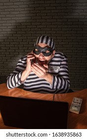 Comic Character Prisoner Telephone Con Man Sitting At A Laptop In A Striped Robe And A Hat In A Black Mask And Cheating On The Phone