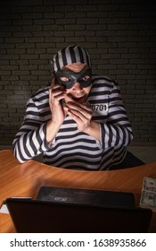 Comic Character Prisoner Telephone Con Man Sitting At A Laptop In A Striped Robe And A Hat In A Black Mask And Cheating On The Phone