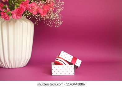 Comic Gift Prank Concept. Jaws In Gift Box Near Vase Flowers Bouquet Pink Background. Sense Of Humor. 