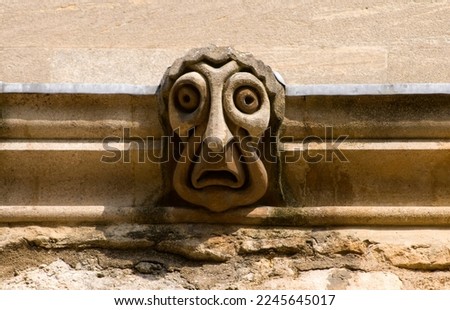a comic stylized gargoyle with a fat face on a college wall in Oxford UK (New College)