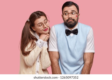 Comic Young Woman With Two Pony Tails Looks With Love At Boyfriend Who Has Red Lipstick On Cheek After Recieving Kiss, Feel Awkward As Have First Date, Wear Elegant Clothes And Big Spectacles