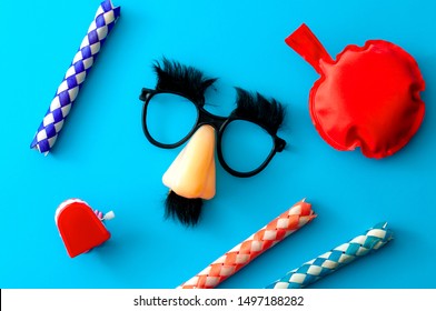 Comical Prank, April Fools Practical Joke And Goofy Disguise Concept Farting Bag, Chattering Teeth, Chinese Finger Trap And Novelty Glasses With Fake Nose And Eyebrows Isolated On Blue Background